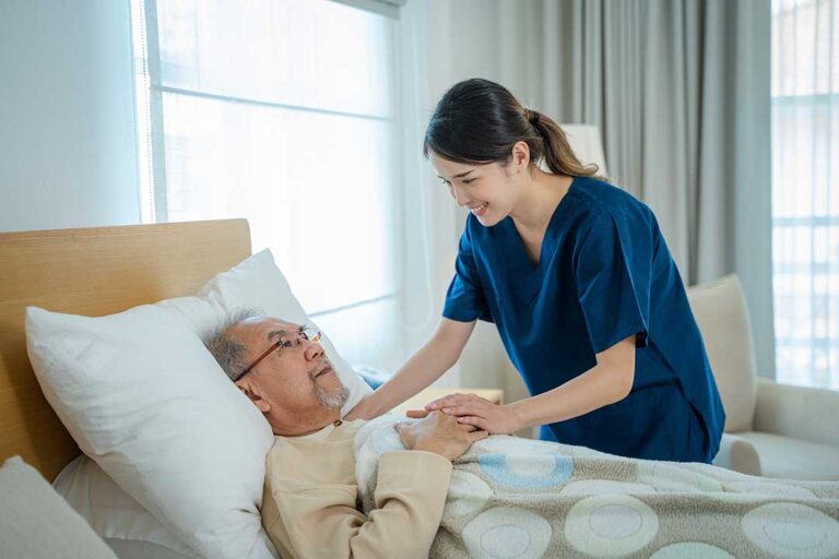A senior resident chats with a nurse while having her blood pressure checked in a bright, home-like community setting.